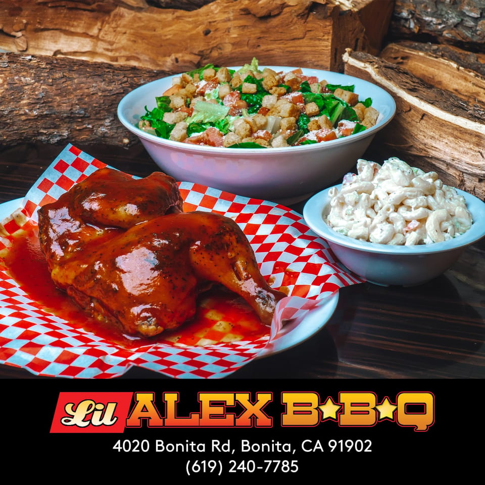 Lil Alex BBQ chicken with sauce, macaroni salad, and green salad against a woodpile background.