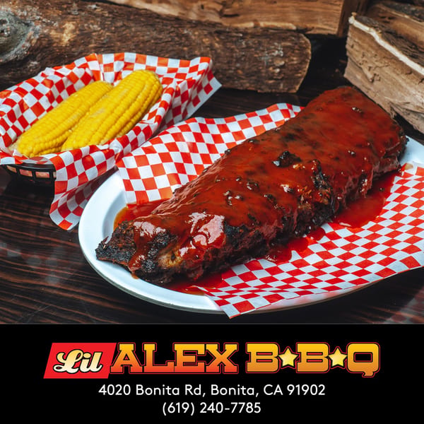 Lil Alex BBQ ribs covered in sauce with two corn on the cob in a basket.