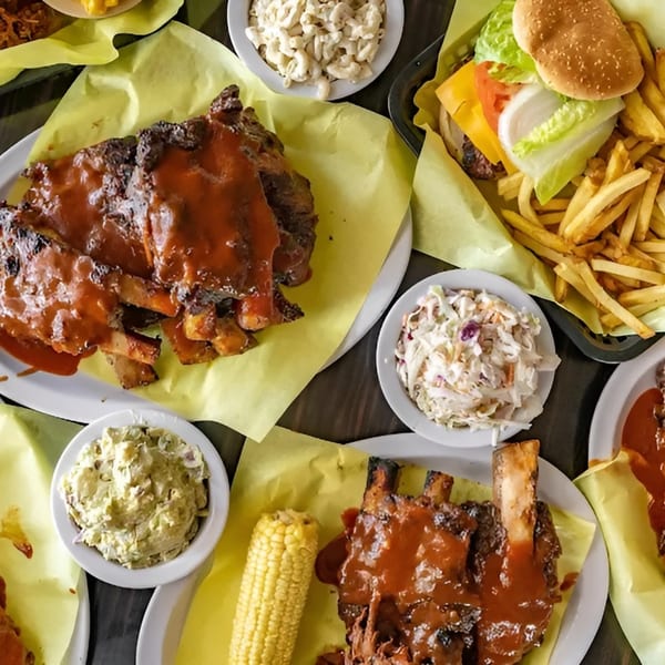 Plates of Lil Alex BBQ ribs, corn, coleslaw, macaroni salad, and a burger with fries.