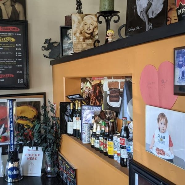 A restaurant interior with Marilyn Monroe decor, a menu board, and a shelf displaying various beverages.